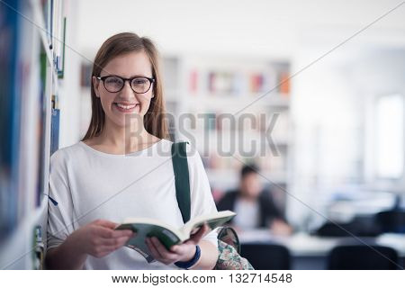 portrait of smart looking famale student girl  in collage school library reading book