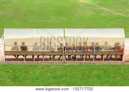Soccer Players And Staff Sit On Bench Beside The Soccer Field