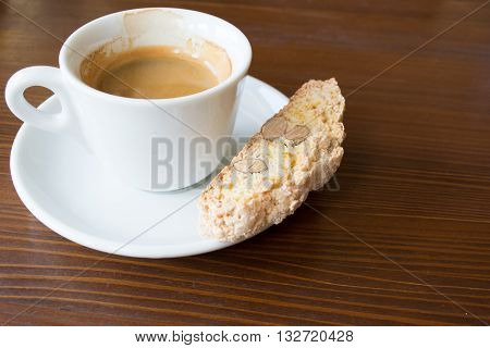 espresso in white demi-tasse with almond and lemon peel biscotti on a dark brown wooden table