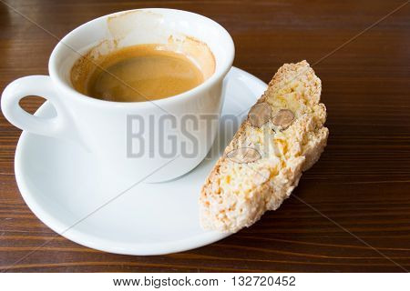 espresso in white demi-tasse with almond and lemon peel biscotti on a dark brown wooden table