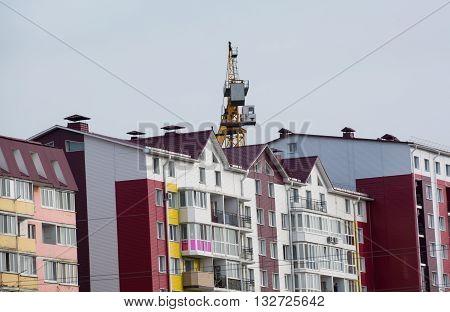 Colored residential home. Tower hoisting cranes over building