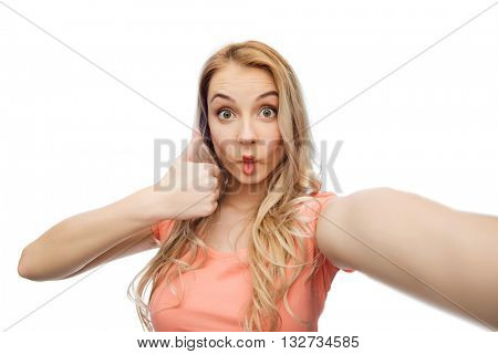 emotions, expressions and people concept - happy young woman taking selfie, making fish face and showing thumbs up