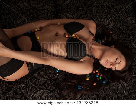 female boobs in black bra. Sexy brunette. Candies in boobs. Fashion hot shot. Girl in black lingerie in hotel.