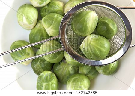 Some fresh brussel sprouts in a sieve.