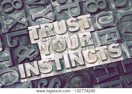 trust your instincts made from metallic letterpress blocks with dark letters background