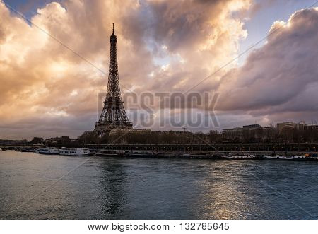 Luminous clouds, Eiffel Tower and the Seine River at sunrise. Port de Suffren, Paris, France