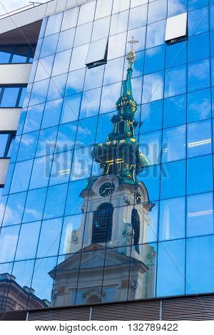 Reflection of old church in modern building windows Stiftskirche Mariahilferstrasse Vienna