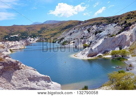 Blue Lake surrounded by white Quartz cliffs mined for gold in the 19th Century at St Bathans, on the Otago Rail Trail, New Zealand south Island