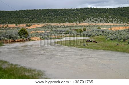 a rusty car frame sits beside the Sevier River in Utah