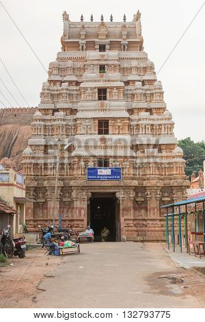 Chettinad India - October 16 2013: The gopuram of the Lord Vishnu temple in Thirumayam village. The battlements of the fort in background. A few people at entrance.