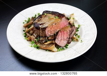 Tasty Beef Mignon sliced steak with mushrooms and herbs on plate