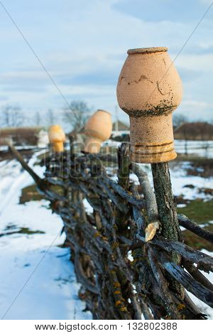 In the old wicker fence hanging pitchers. Rural farm. End of winter thaw.
