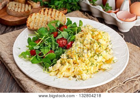 Scrambled eggs on plate with vegetables and grilled toast