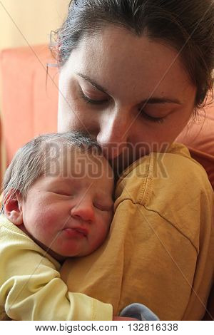 A baby being held in arms by a mother.