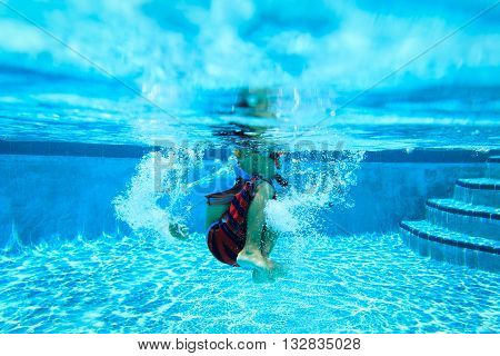 Underwater diving little boy with mask in swimming pool