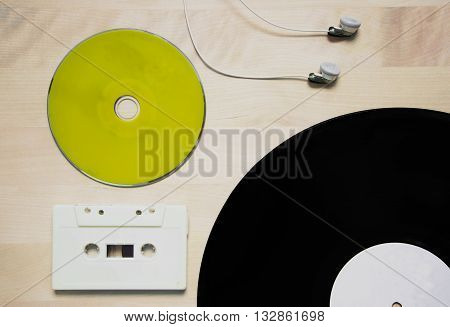 music in green cd cassette tape vinyl disk and earphone on wood background