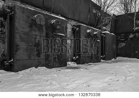 Nuclear bunker. Nuclear bomb shelter. Old abandoned Soviet Cold War bunker in forest. Locked steel gate with ventilation vents. Black and white photo.