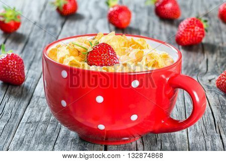 corn flakes with milk and strawberry in a red cup on an old rustic table studio lightrs close-up top view