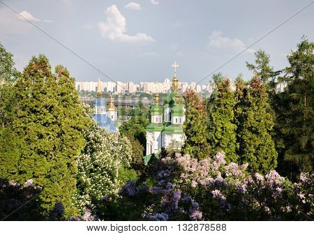 Orthodox church against the sky and the lush spring garden city