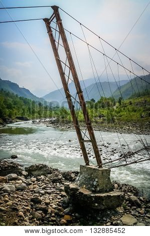 Damaged bridge over the Bhote khosi river, flowing through the beautiful mountain valley in the mountains of Nepal