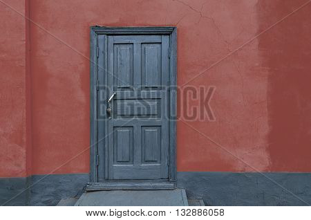 Rustic vintage old house red wall with gray wooden door. Copy scape