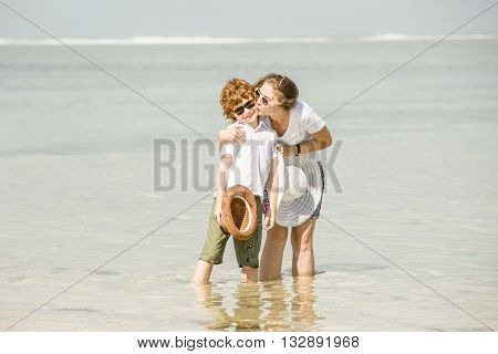 Yound caucasian mother and son having great family time on tropical beach on vacation