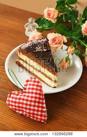 piece of cake and red heart on wooden background. Valentines day background.