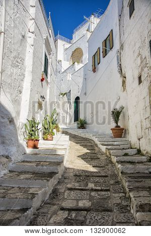 Narrow and old street or alley in italian town of Ostuni in Puglia. Historical view of Italy