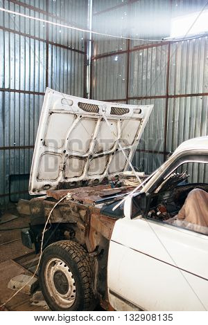 Disassembled old car in garage close-up. Old car on servicing in garage. Repairing of old Russian car at service station.