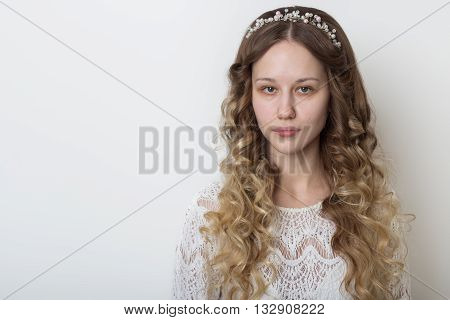 young beautiful young girl with long curly hair, no makeup with a clean face with a wreath on his head portrait in the studio on a white background