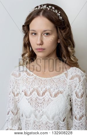 young beautiful young girl with long curly hair, no makeup with a clean face with a wreath on his head portrait in the studio on a white background