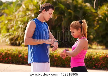 Young people doing sport activities girl and friend running using fit watch man and woman jogging on the street. Concept of eisure health recreation fitness exercising training workout