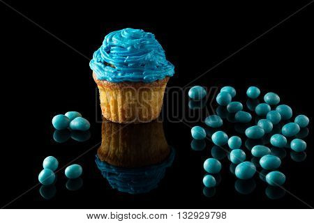 one blue muffin on black with reflection