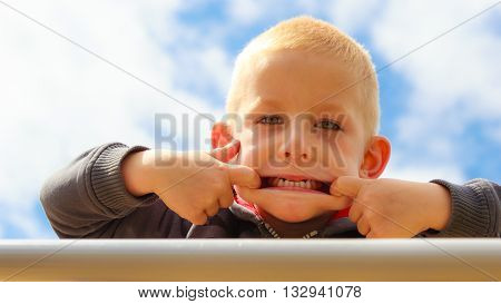 Funny child kid making silly face. Happy boy having fun. Childhood expression.