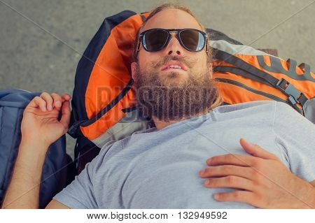 Closeup of handsome male backpacker tourist napping on a bench and baggage at the station
