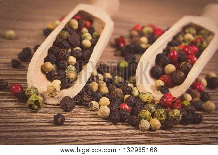 Vintage photo Heap of fresh colored pepper with wooden spoon lying on wooden table seasoning for cooking concept for healthy nutrition