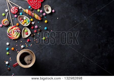 Colorful candies and coffee cup on stone background. Top view with copy space