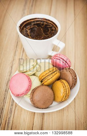 Cup of black coffee with french colorful macarons. Sweet delight. Food and drink. Vertical composition. Tasty macarons.