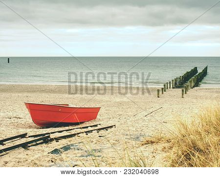Abandoned Red Paddle Boat On Sandy Beach Of Sea.  Smooth Water Level Within Morning Windless. Dramat