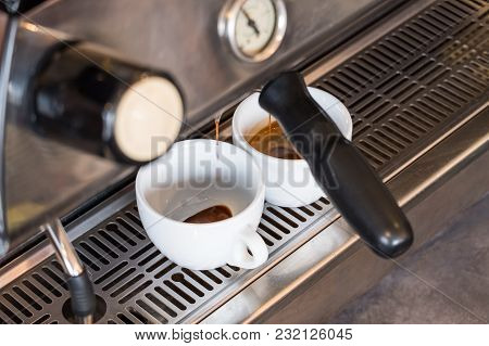 Fresh Espresso Dripping From Portafilter Of Coffee Machine Into White Cup