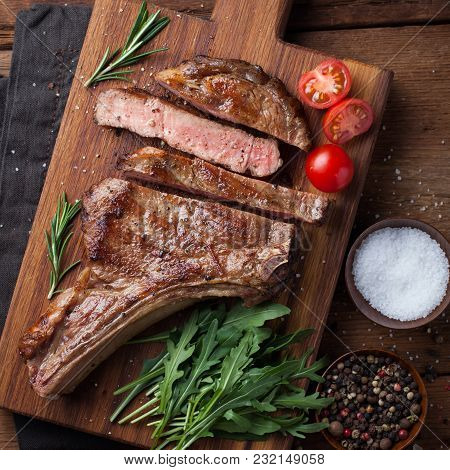 Grilled Cowboy Beef Steak, Herbs And Spices On A Rustic Wooden Background. Top View.