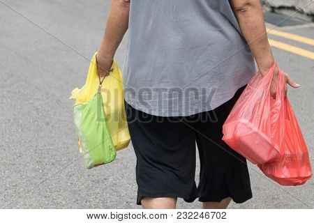 Woman Carrying Plastic Bag In Her Hand After Shopping At Street Market In Downtown.inside The Plasti