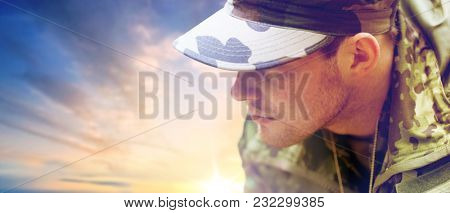 army, national service and people concept - close up of young soldier in military uniform over sky background