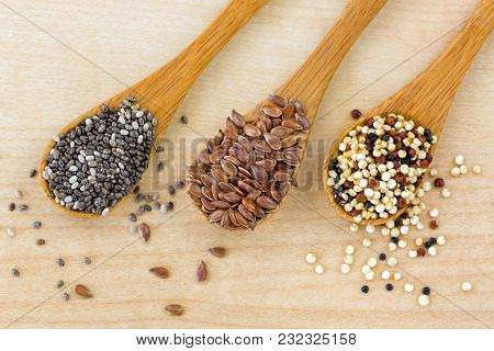 Dried Chia seed, Linseed flaxseed, Quinoa seed tri-color blend on wooden spoon, wood background