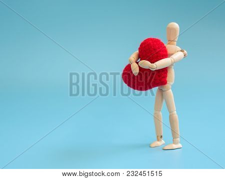 Wooden Puppet Standing And Holding A Red Heart On The Blue Screen Background. Wooden Puppet Holding 