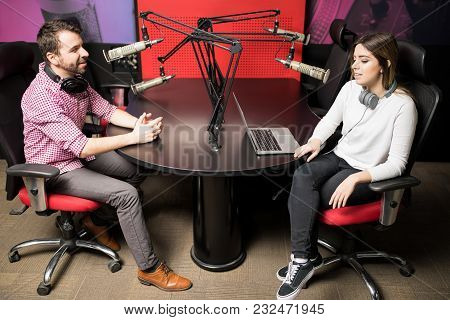 Young Man And Woman Presenters In Radio Station Hosting A Live Radio Show