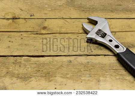 Adjustable Wrench On A Wooden Workbench . On The Wooden Background