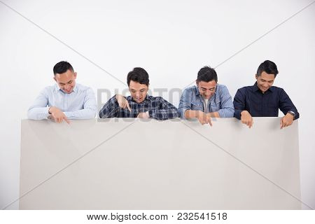 Four Man Are Pointing In The Blank Space And Looking Into The Camera