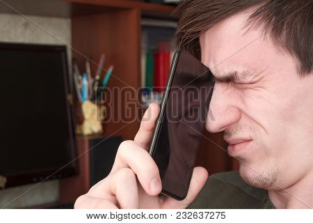 The Guy Tightly Squeezed His Eyes, Closed The Rum With A Black Smartphone, In The Workplace