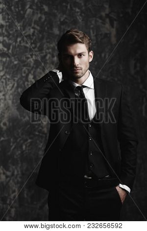 Portrait of a handsome man in an elegant suit on a grunge background. Studio shot.